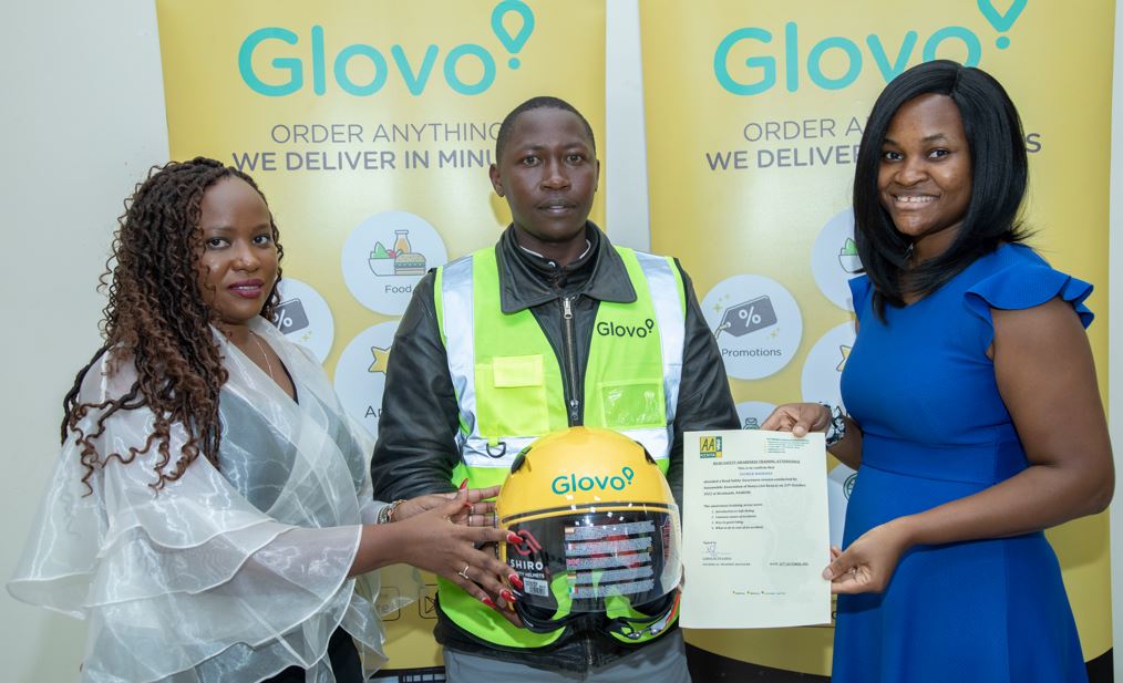 Glovo Kenya General Manager Caroline Mutuku (left) hands over an helmet to Dennis Mutinda, a Glovo rider during the couriers pledge launch. Looking on is Tokunbo Ibrahim, Glovo's Head of Government Relations SAA.